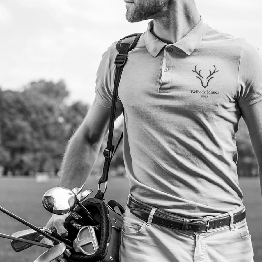 Golfer wearing Welbeck Manor Golf branded polo with clubs